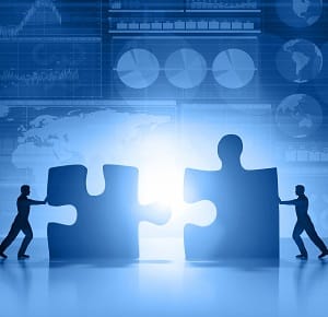 Silhouette of business people moving and joining pieces of jigsaw puzzle on a business and stock market blue background, with charts, diagrams, world maps and data arranged on grid and tables. World maps showing continents and countries with economy data and growth diagrams. Light glowing from the center. Copy space on bottom.