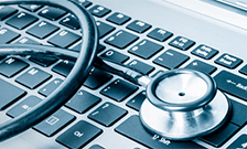 Stethoscope resting on a computer keyboard representing IT system diagnostics in the healthcare industry.