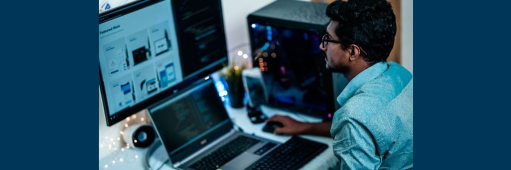 Man at a computer and monitor trying to resolve a computer issue