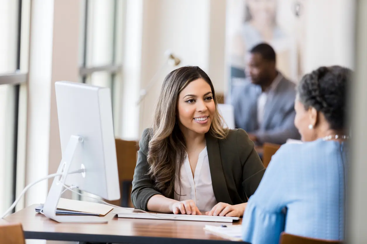 Bank teller pulling customer data via secured IT services for financial institutions to provide personalized customer service to customer.