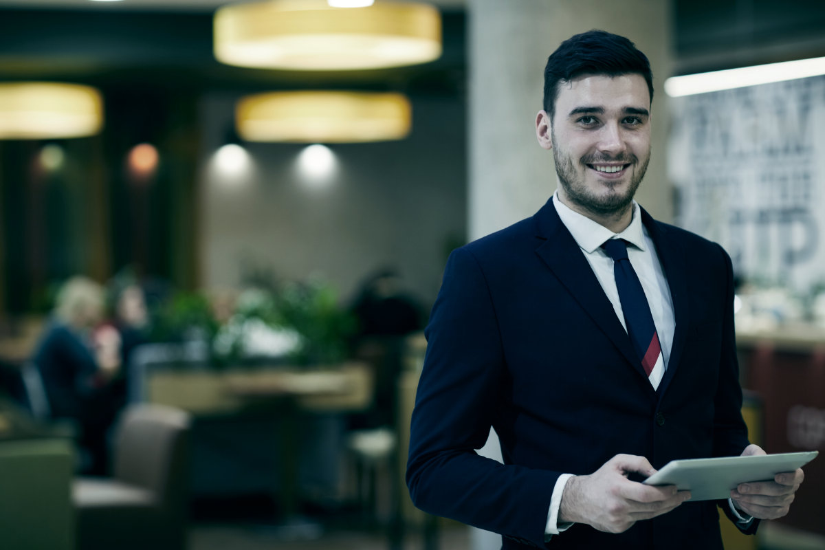Hospitality professional welcoming guests with tablet.