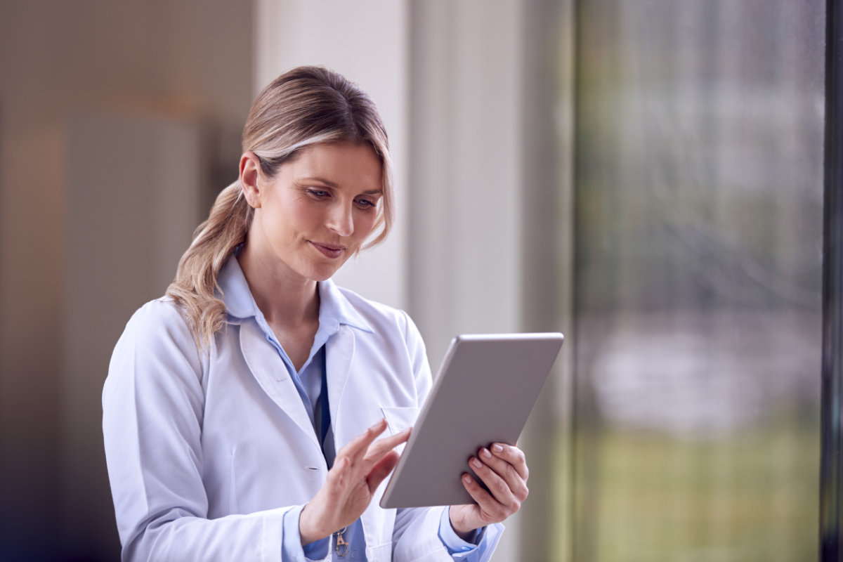 Healthcare professional reviewing sensitive information on tablet.