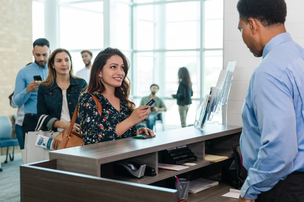 Woman engaging with bank teller to conduct personal banking.