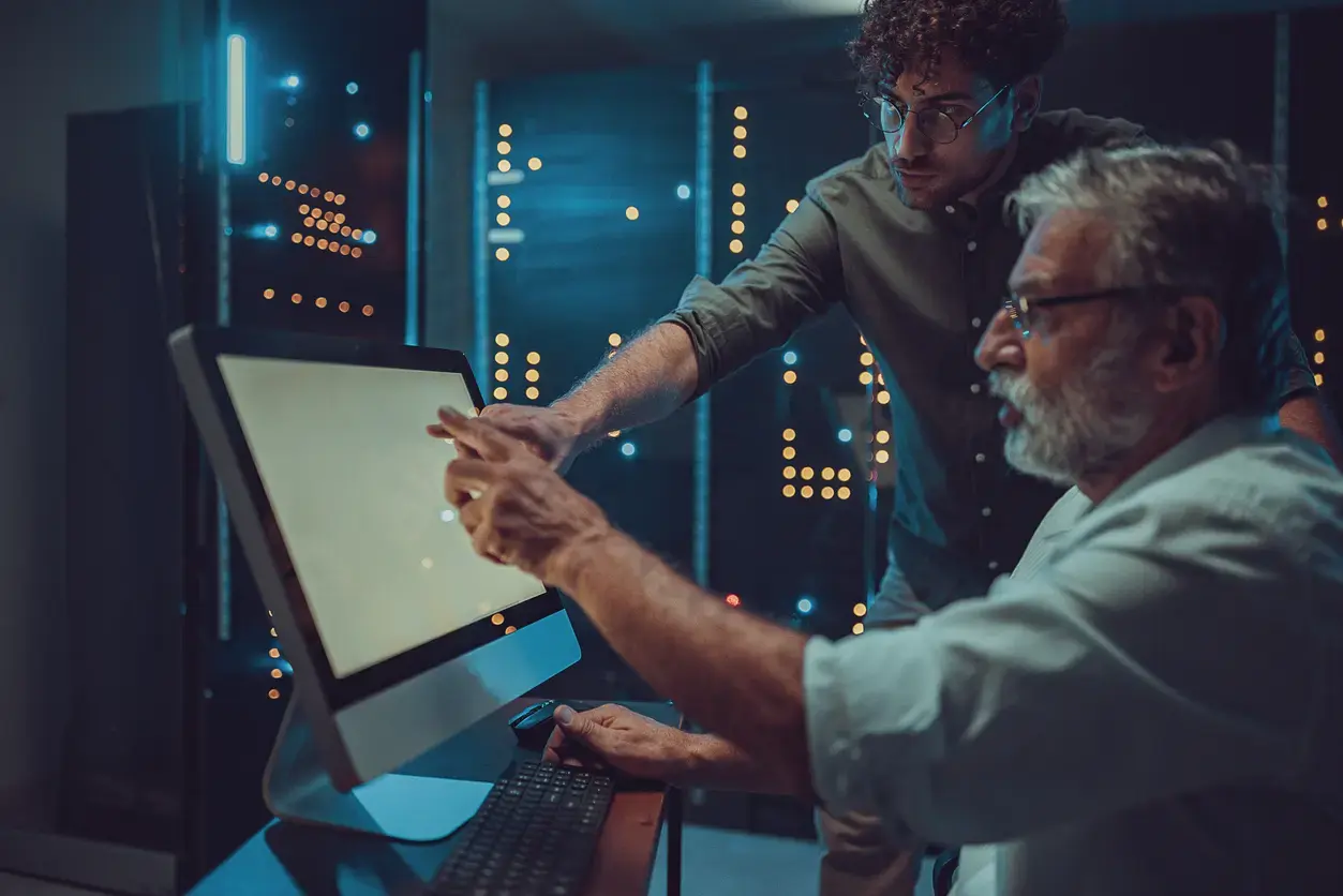 Two IT professionals analyzing risk on a desktop screen in a data center environment.
