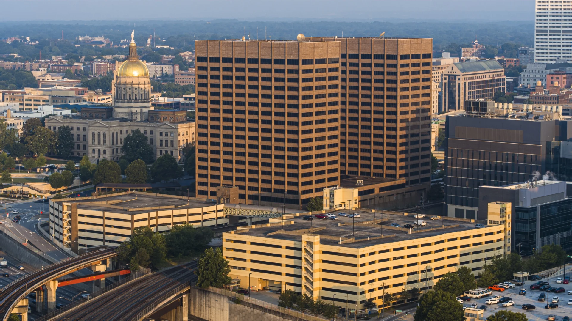Aerial view of downtown Atlanta at dusk showing the Georgia State Capitol and surrounding office buildings under a warm evening light.
