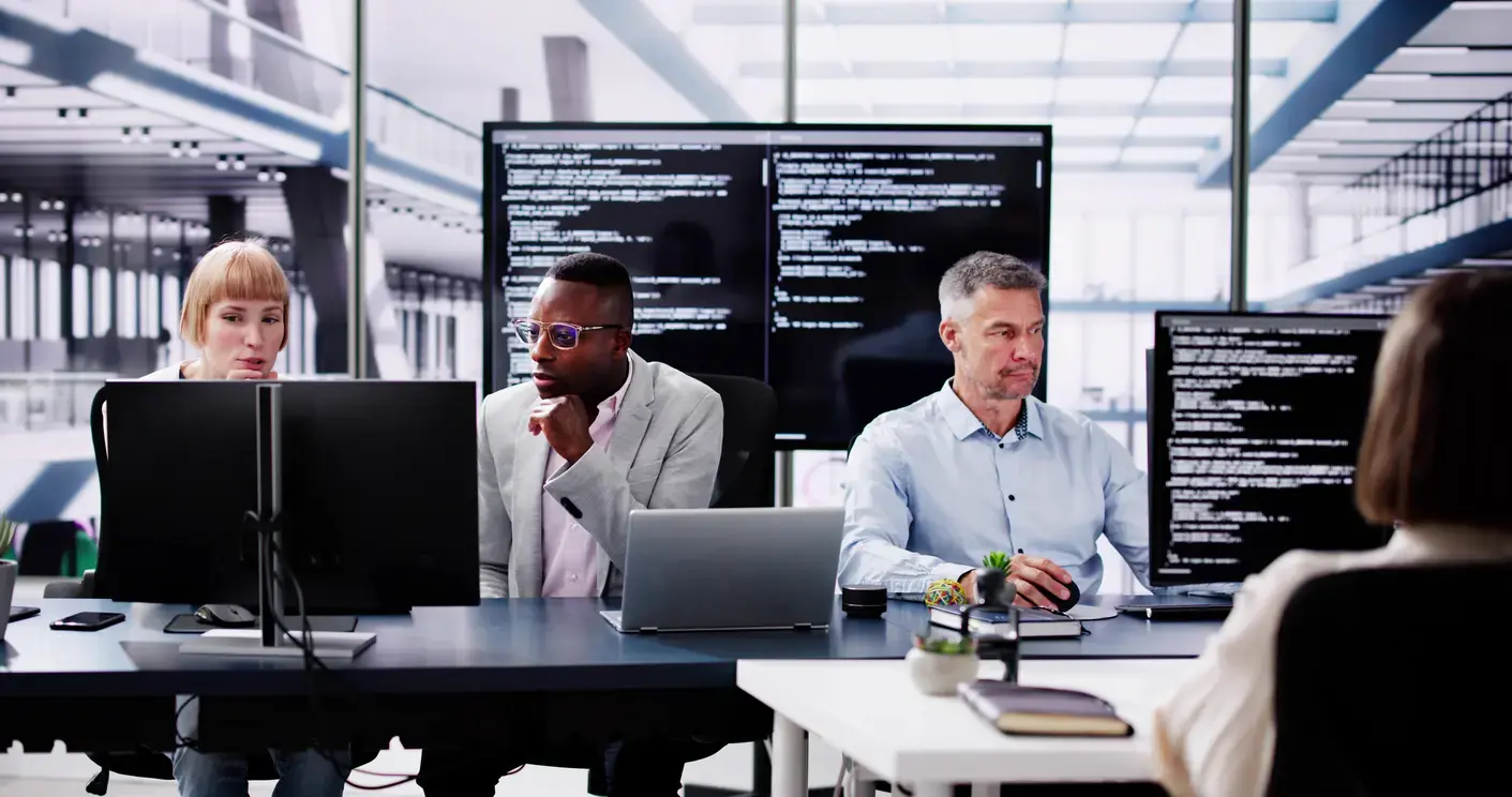 Professional conducting observability assessment and system monitoring at desk with multiple monitors displaying code.