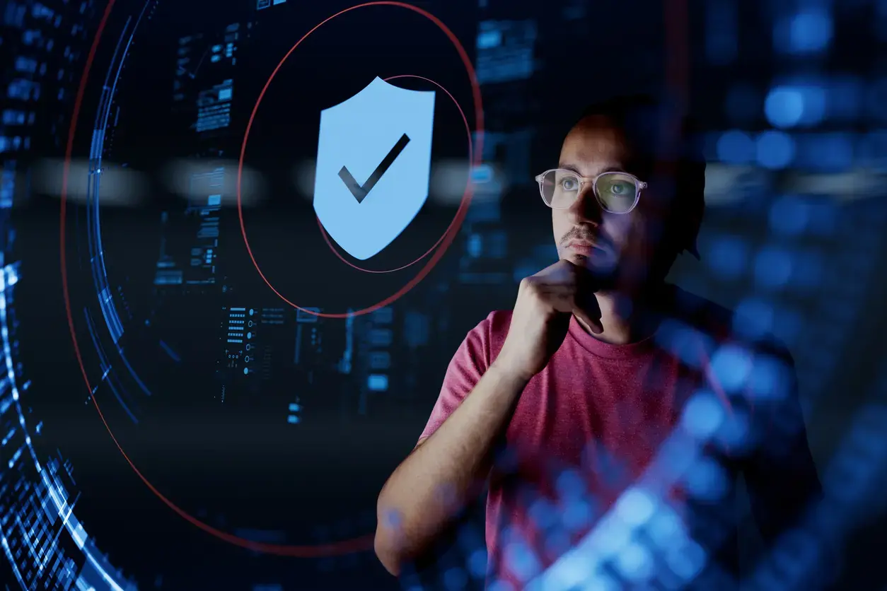 Professional examining cybersecurity data with a digital shield icon.