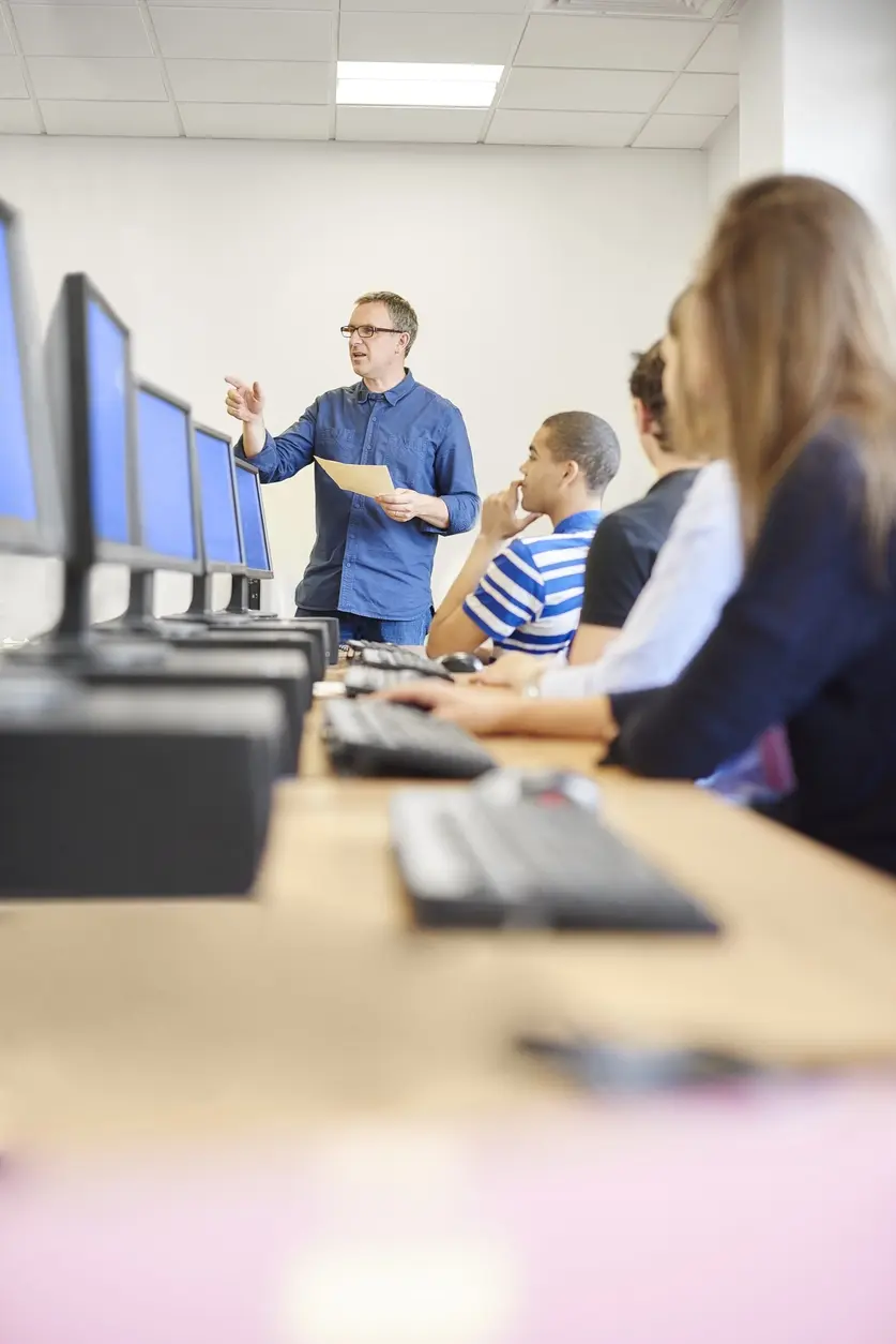 Instructor guiding students in a computer lab, symbolizing the TekStream Workforce Development Center.