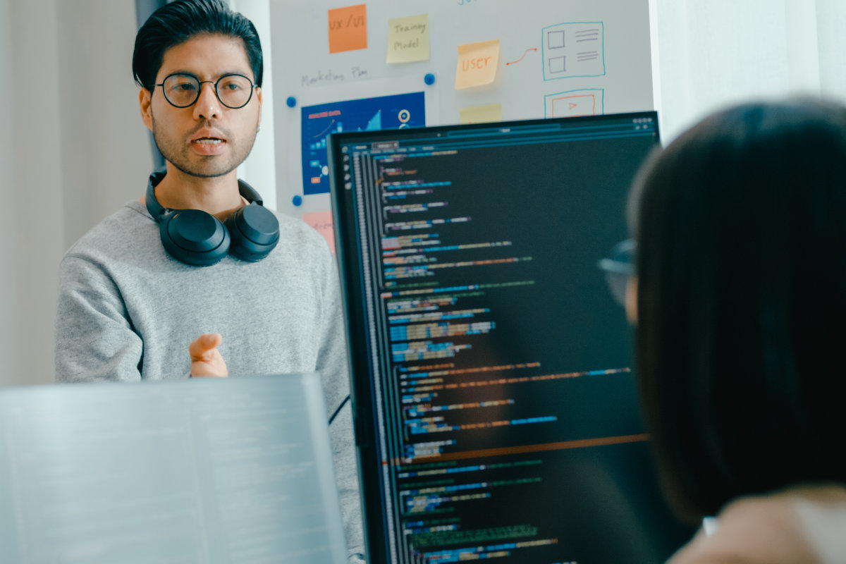 Developer explaining code on a monitor during a team discussion.
