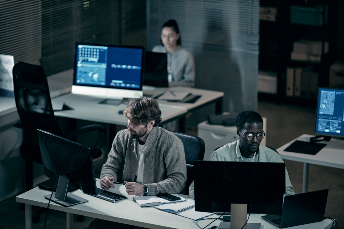 Software development team collaborating in a office with multiple computer workstations.